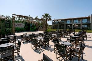 Terrasse des Eliros Mare Beachfront Hotels mit vielen Tischen und Stühlen.