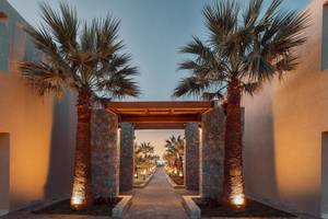 Eingang zum Eliros Mare Hotel mit Palmen und beleuchtetem Weg