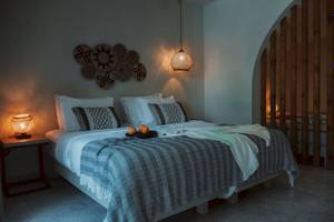 Schlafzimmer im Eliros Mare Hotel mit Bett, Kissen, Decken und Lampen