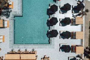 Luftbild vom Poolbereich des Eliros Mare Hotels mit Liegestühlen und Sonnenschirmen.