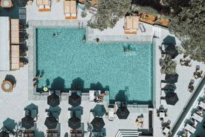 Luftaufnahme des Pools im Eliros Mare Hotel mit Gästen und Sonnenschirmen.