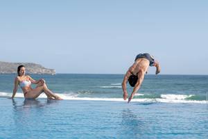 Mann springt ins Wasser im Außenpool am Cretan Dream Resort & Spa.
