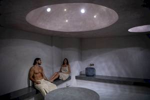 Sauna-Raum im Cretan Dream Resort & Spa mit einem Mann und einer Frau, die auf Bänken sitzen.