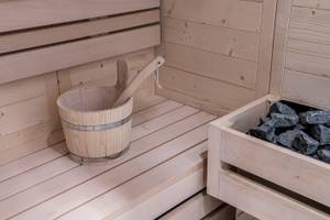 Innenraum einer Holzsauna mit einem Eimer und Steinen