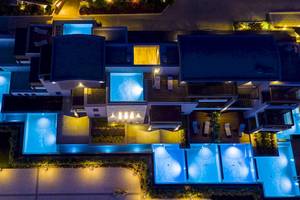 Luftaufnahme des Cretan Dream Resort & Spa bei Nacht mit blau beleuchteten Swimmingpools und angelegtem Garten.