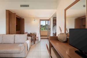 Innenansicht des Cretan Dream Resort & Spa mit Wohnzimmer, Couch, Tisch und Fernseher.