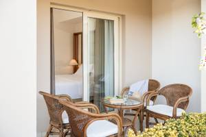 Ein Balkonbereich mit einem Tisch, Stühlen und einem Bett im Hintergrund im Cretan Dream Resort & Spa.