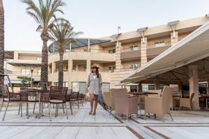Frau im Sommerkleid und Hut geht vor dem Cretan Dream Resort & Spa entlang