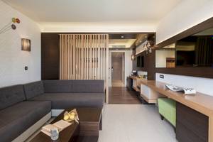 Inneneinrichtung des Cretan Dream Resort & Spa mit Sofa, Couchtisch, Büchern und Fernseher.