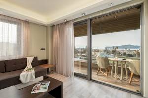 Wohnzimmer des Cretan Dream Resorts & Spa mit Meerblick, inklusive Sofa, Tisch und Panoramafenstern.