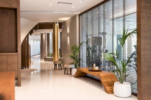 Innenbereich des Cretan Dream Resort & Spa mit Holzmöbeln, Pflanzen und einer Wendeltreppe.