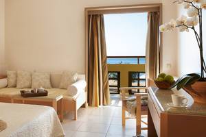 Hotelzimmer im Grecotel Meli Palace mit einem Sofabett, einem Schreibtisch und einem Ausblick auf das Meer.