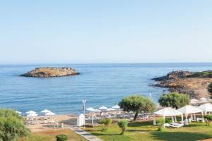 Luftaufnahme des Grecotel Meli Palace Strands mit vielen Sonnenschirmen und Liegen