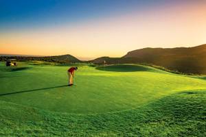 Golfer auf dem Golfplatz des Grecotel Meli Palace während des Sonnenuntergangs.