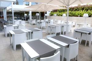 Außenbereich des LABRANDA Bronze Playa Hotels mit weißen Tischen und Stühlen unter Schirmen.
