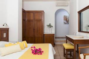 Innenansicht eines Zimmers im Chrissi Amoudia Hotel mit Bett, Dekor und Möbeln.