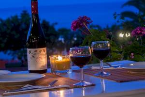 Abendessen bei Kerzenlicht im Chrissi Amoudia mit Weinflasche, zwei Gläsern und Kerze in einem Glas.