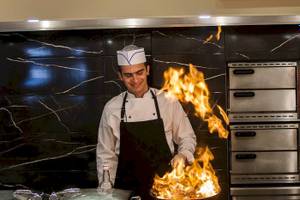Koch im Chrissi Amoudia Hotel mit brennenden Flammen in der Küche