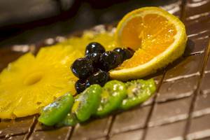 Nahaufnahme einer Schokoladenplatte mit Ananas, Kiwi, Blaubeeren und Orangenscheibe im Chrissi Amoudia Hotel.