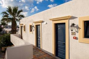 Eingangsbereich des Chrissi Amoudia Hotels mit weißen Wänden, blauen Türen und einer Palme