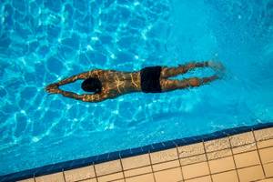 Ein Mann schwimmt im Pool von Chrissi Amoudia Hotel.