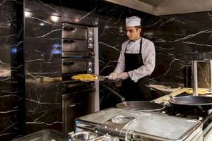 Koch im Chrissi Amoudia Hotel zieht Pizza aus dem Ofen