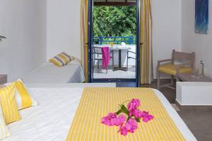 Doppelzimmer mit Balkon im Hotel Chrissi Amoudia mit Blick auf eine Terrasse mit Tisch und Stühlen.