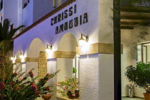 Das Chrissi Amoudia Hotel mit beleuchtetem Eingang und Pflanzen davor.