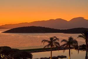 Abendlicher Sonnenuntergang im Hotel Minos Palace Hotel & Suites mit Blick auf das Meer und die Berge.