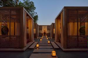 Lounge-Bereich des Minos Palace Hotel & Suites mit Holzhütten und beleuchteten Wegen.