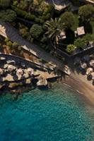 Luftaufnahme des Minos Palace Hotel & Suites am Strand mit Palmen und Sonnenschirmen.