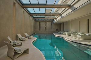 Innenpool des Minos Palace Hotel & Suites mit Lounge-Sesseln und einem Glasdach.