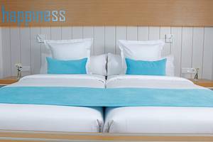 Ein Doppelbett mit weißen Laken, blauen Kissen und einem blauen Bettlaken im LABRANDA Bronze Playa Hotel.