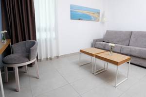 Das Hotelzimmer des Labranda Bronze Playa mit Sofa, Beistelltischen und Tisch mit Blumenvase.