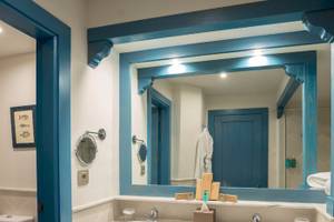 Badezimmer im LIVVO Volcan Lanzarote Hotel mit blauen Akzenten und einem Spiegel.