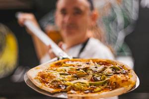 LIVVO Volcan Lanzarote Hotel-Küchenpersonal hält eine Pizza auf einem Pizzaliefertraeger