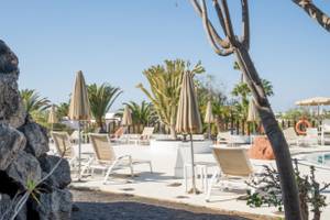 Pool-Lounge-Bereich im LIVVO Volcan Lanzarote Hotel mit Sonnenliegen, Sonnenschirmen und Pflanzen.