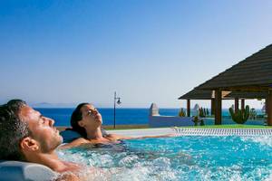 Paar genießt im Pool des LIVVO Volcan Lanzarote Hotels mit Blick auf das Meer.