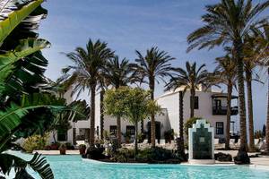 Außenpoolbereich des LIVVO Volcan Lanzarote Hotels mit Palmen und weißen Gebäuden