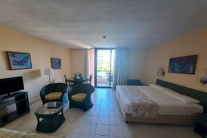 Zimmer im Muthu Playa Varadero Hotel mit Bett, Tisch, Stühlen und Fernseher.