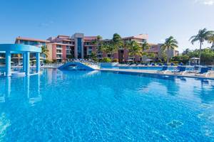 Der Außenpool des Muthu Playa Varadero Hotels mit vielen Liegestühlen und Palmen.