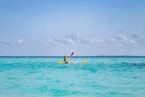 Eine Frau paddelt auf dem Ozean vor dem Nova Maldives.
