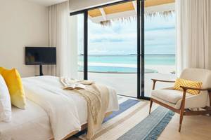 Schlafzimmer im Nova Maldives Hotel mit Meerblick, einem großen Bett und einem Fernseher.