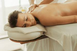 Massage-Behandlung im Nova Maldives Hotel, eine Frau genießt eine Rückenmassage.