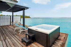 Ein Whirlpool auf einer Holzterrasse mit Blick auf das Meer im Nova Maldives Hotel.
