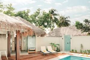 Privatpool in der Villa des Nova Maldives Hotels mit Sonnenliegen und Tisch.