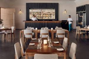 Restaurant-Innenbereich des Nova Maldives mit Tischen, Stühlen und Bar.