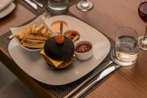 Nova Maldives Hotel Essen auf Tisch mit Burger, Pommes, Glas Wasser und Wein