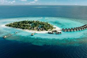 Luftaufnahme der Nova Maldives Insel mit vielen Wasserbungalows und einem Steg.