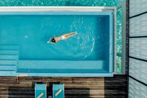 Ueberblick des Schwimmbeckens im Nova Maldives Hotel mit einer Frau, die schwimmt.